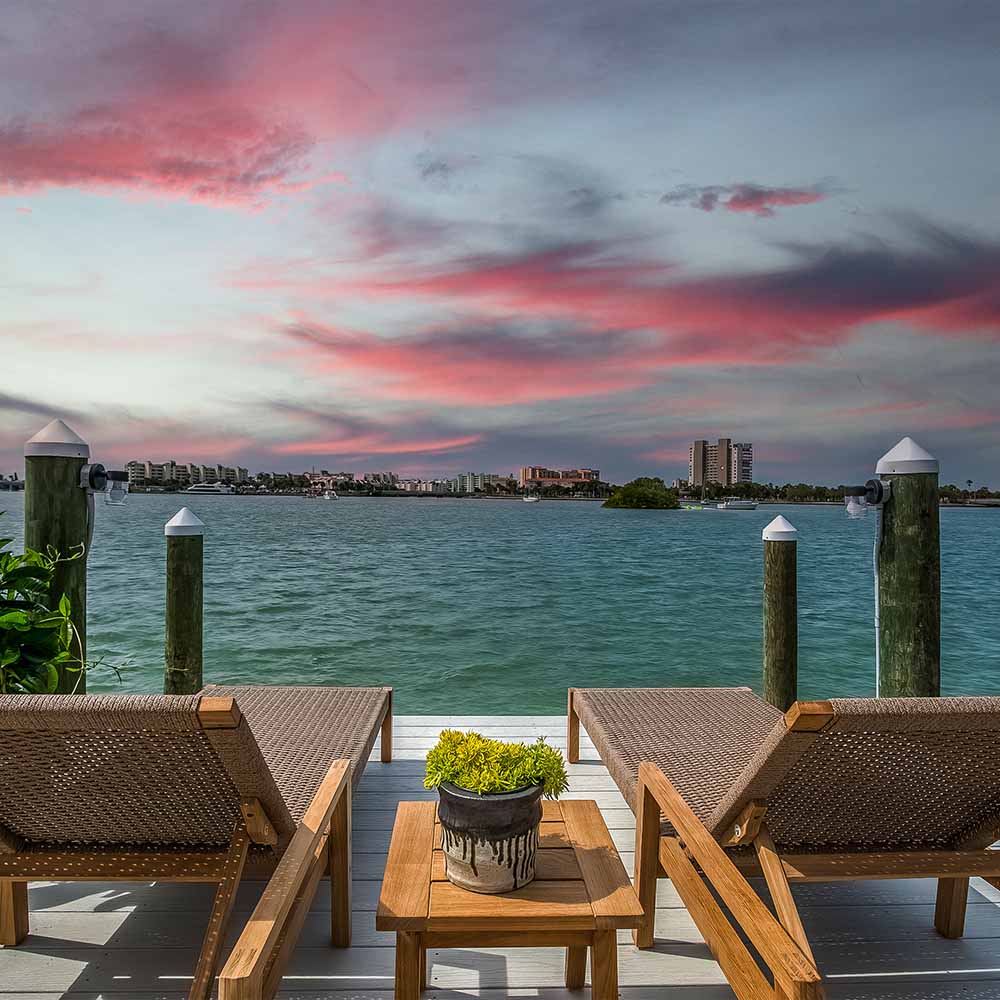 Outdoor lounge set with two woven loungers and a teak coffee table on deck