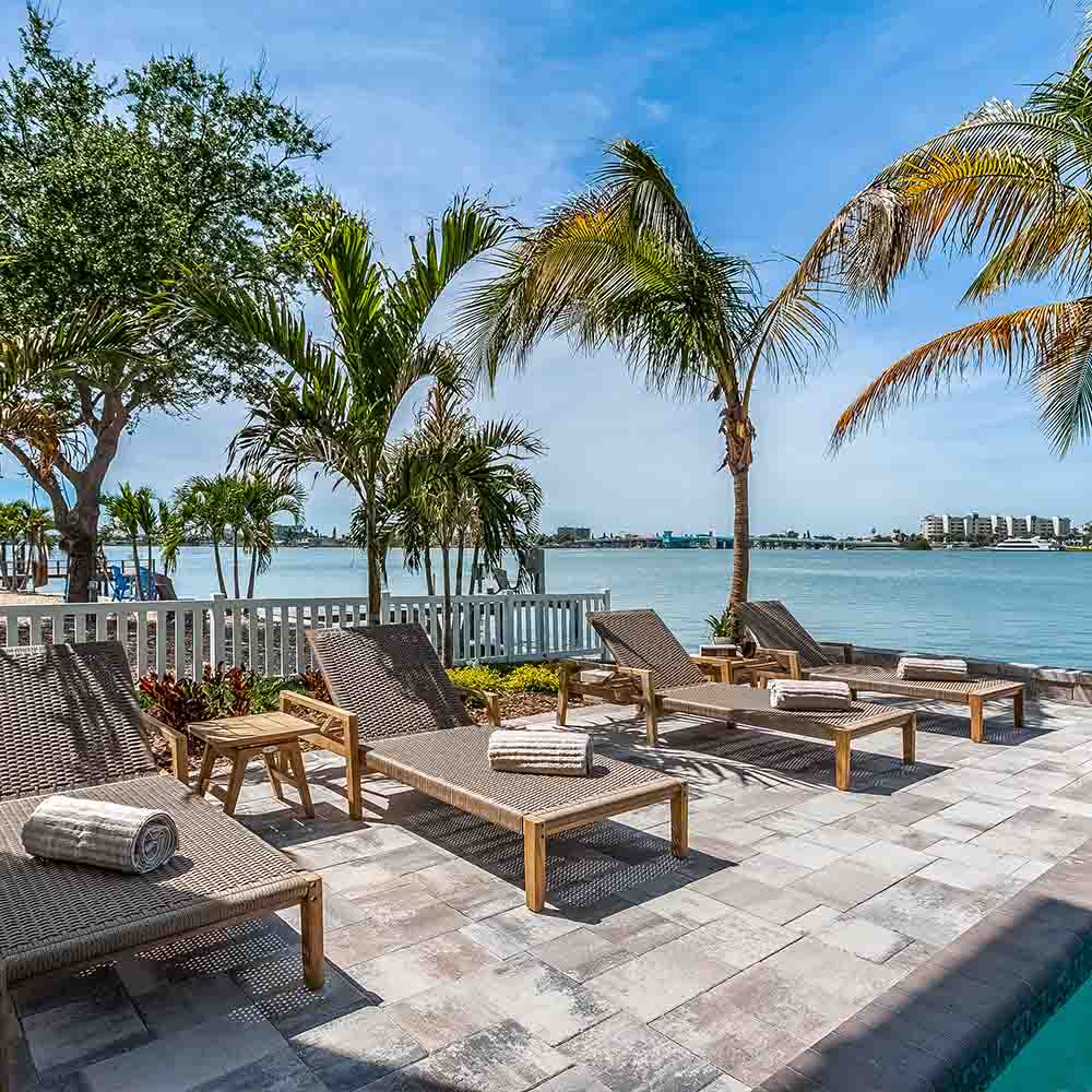 Outdoor lounge set with multiple woven loungers and teak side table