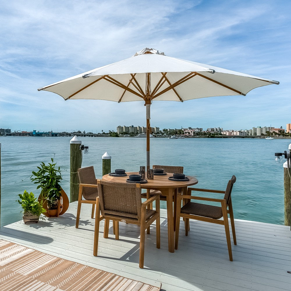 Outdoor dining table with four woven chairs under a cantilever umbrella