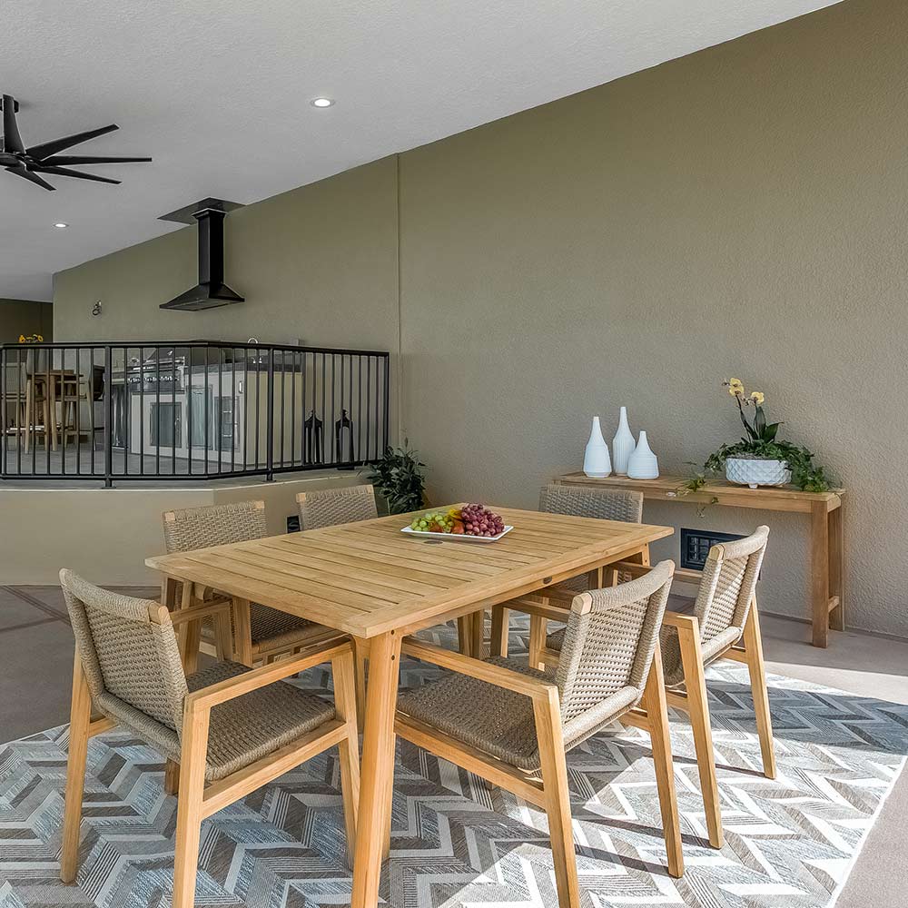 Teak dining table with slatted top and four chairs arranged around it