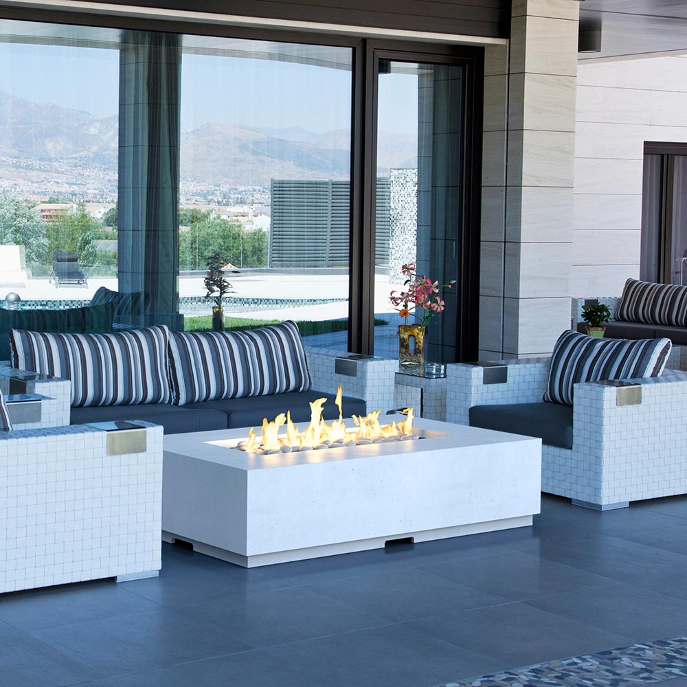 White square outdoor propane gas fire table with visible flames in central burner