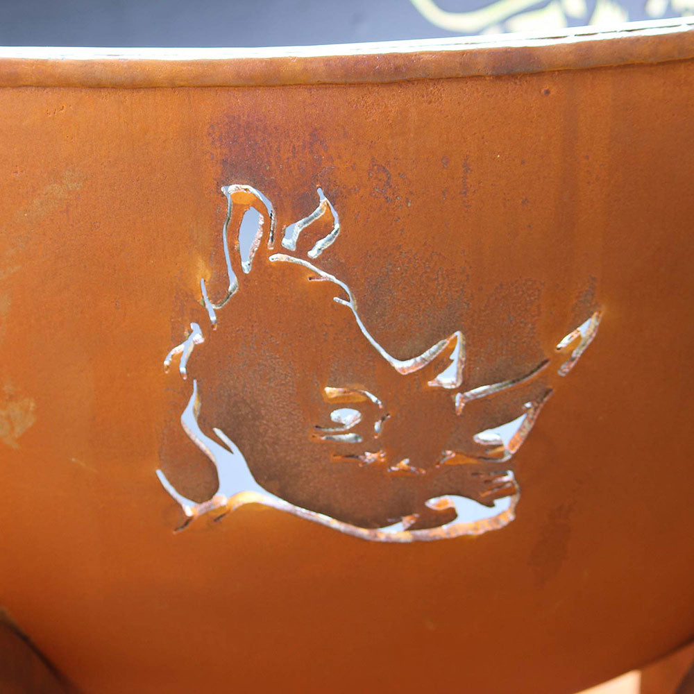 Close-up of orange gas fire pit bowl featuring raised animal relief emblem.