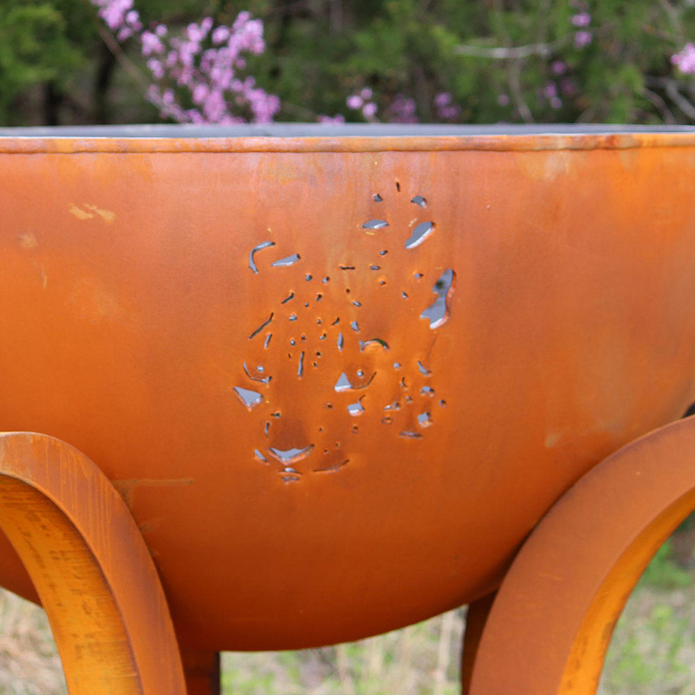 Orange gas fire pit bowl side with raised animal relief pattern.