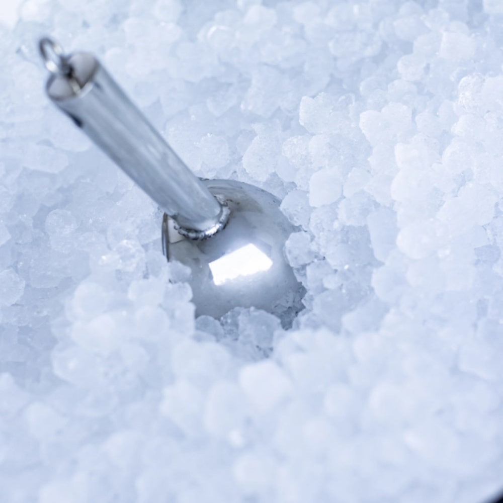 Nugget ice in bin with metal scoop resting on ice cubes