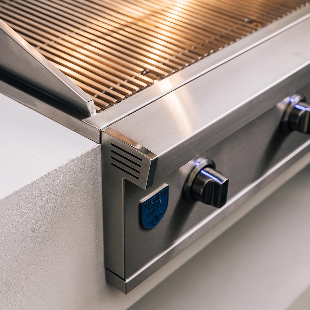 Stainless gas grill side panel with control knob and vent near the burner box.