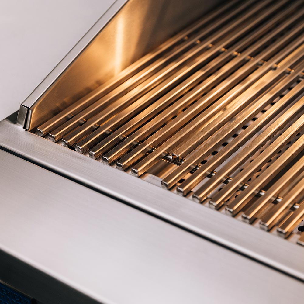 Stainless gas grill grate bars with glowing heat beneath the cooking hood.
