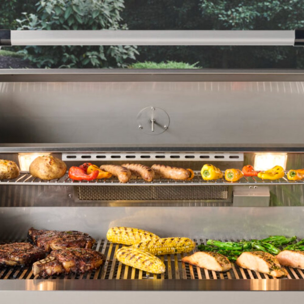 Open built-in gas grill showing cooking grates with vegetables and sausages