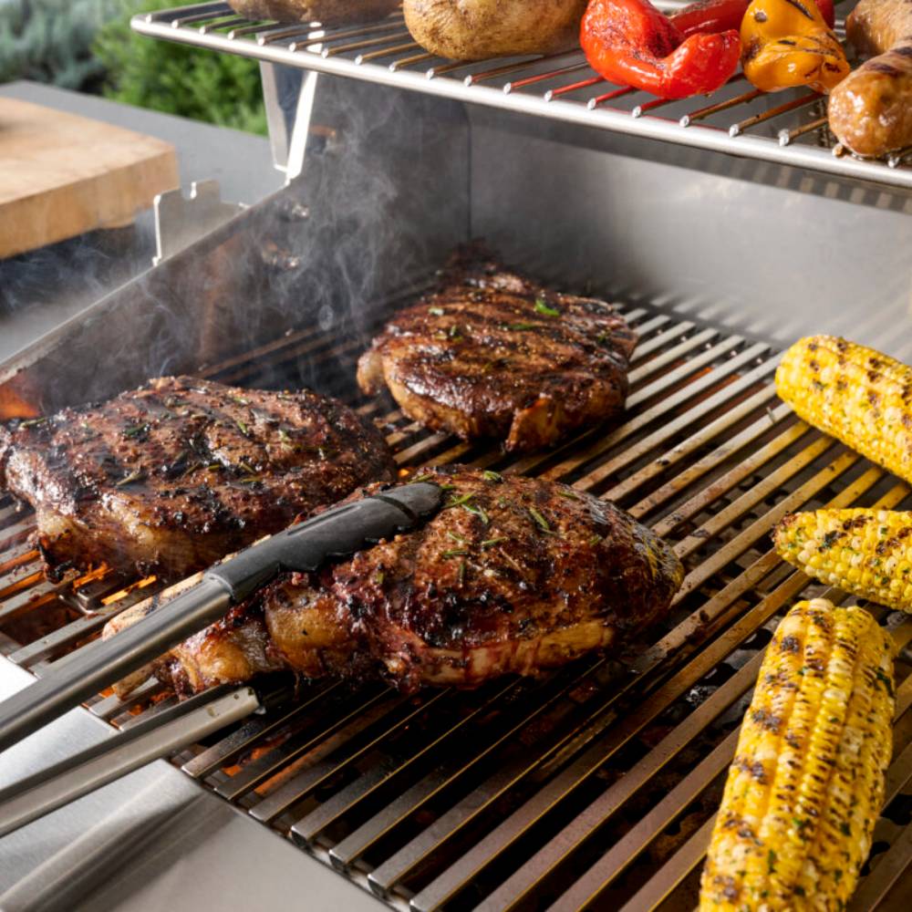 Built-in gas grill with burgers and corn on grates during cooking