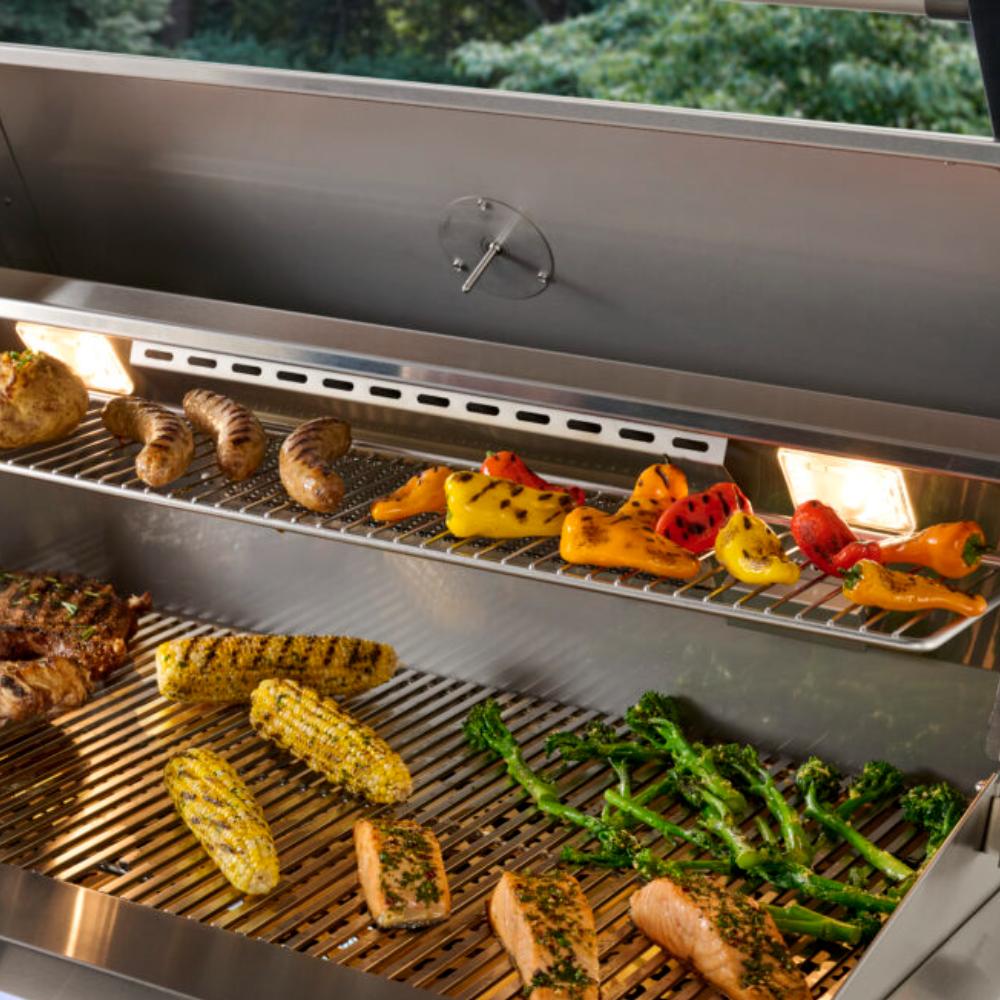 Open stainless steel built-in grill with vegetables and meat on wire grates