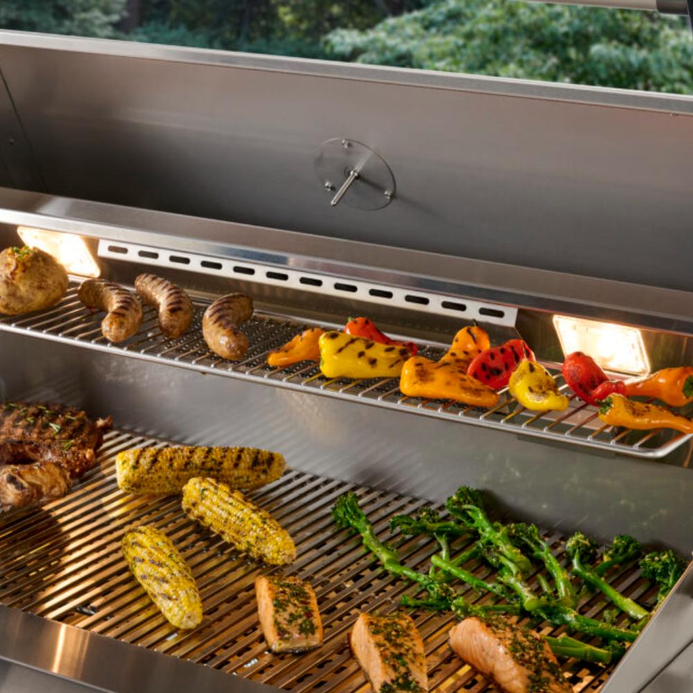 Built-in gas grill interior with sausages, steaks, peppers, and greens on grates