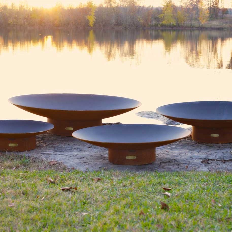 Three round wood fire pits with orange bases and black rims, flames visible