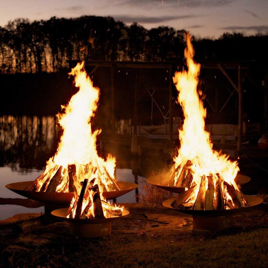 Wood fire pit with tall flames burning in the round metal bowl