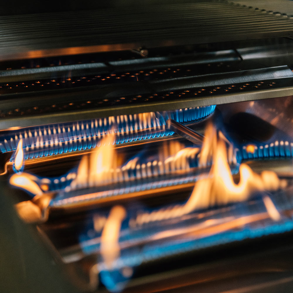 Gas grill interior with glowing blue burners and orange flames