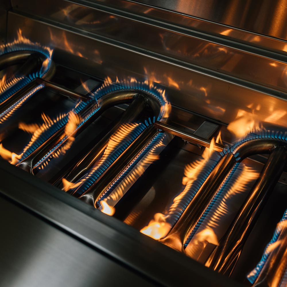 Gas grill burners with orange flames across the grate area
