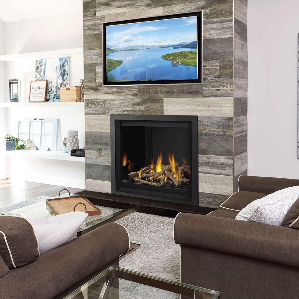 Black gas fireplace insert with burning logs, set in gray stone surround