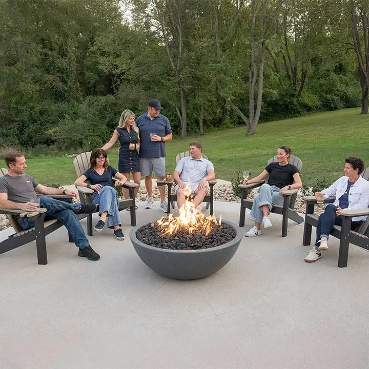 Group of people sitting around a fire pit in a backyard setting