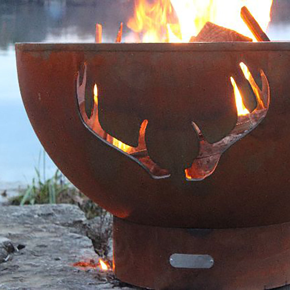 Front of steel fire pit with antler cutouts and flames visible through openings