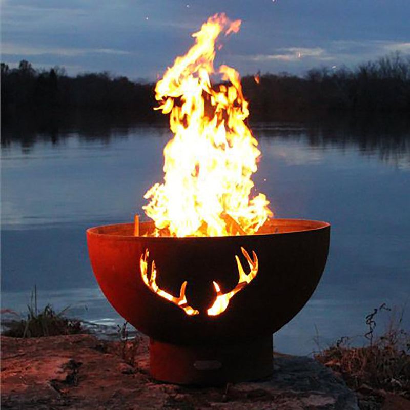 Outdoor fire pit with antler cutout front and tall flames rising from the bowl