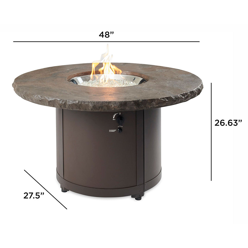 Round fire pit table with dark stone-look top and dark base, flame burning in center