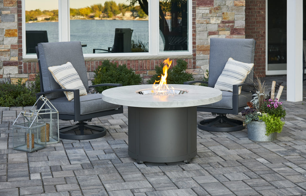 Round fire pit table with light marble top and dark base, flames rising from center
