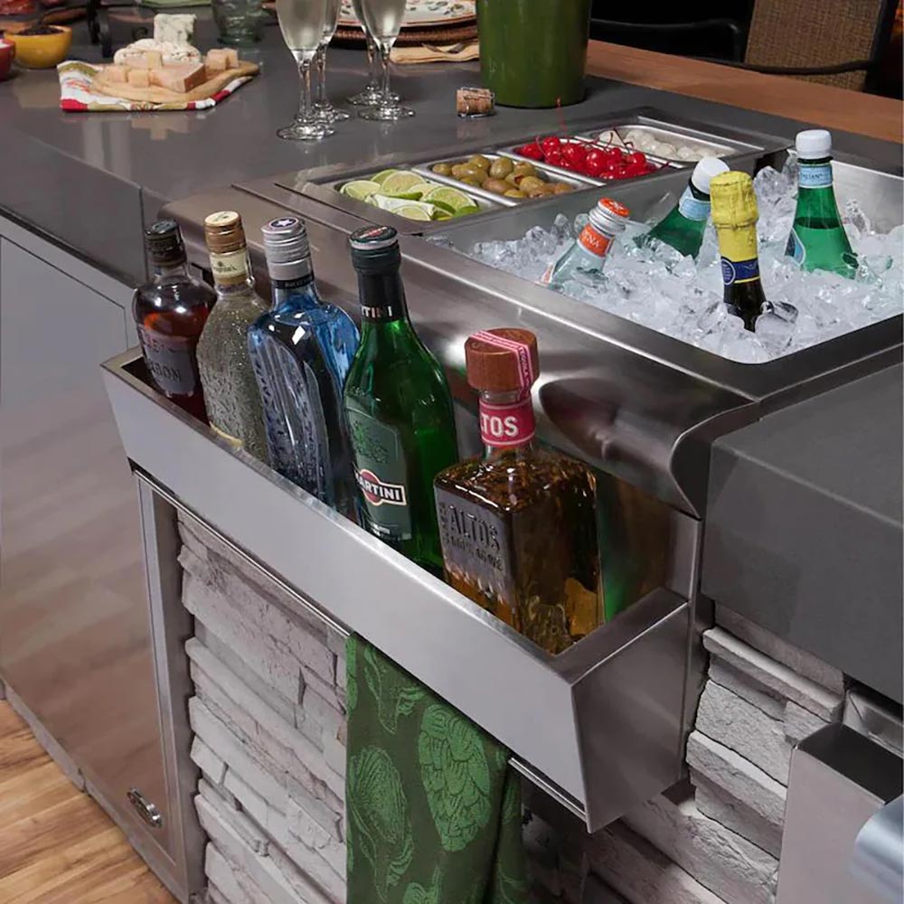 Stainless steel beverage chiller sink with open cabinet holding bottles and ice bin
