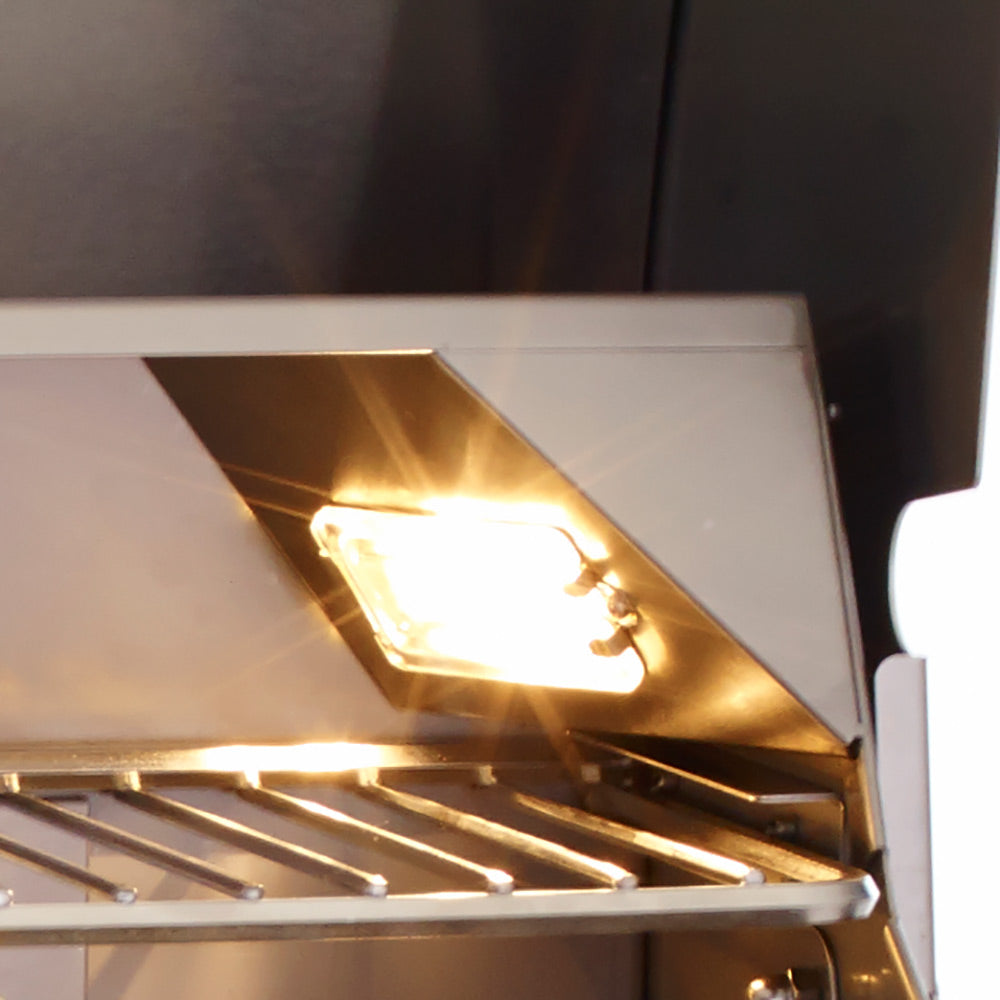 Gas grill burner area with glowing flame under the hood, open cooking chamber