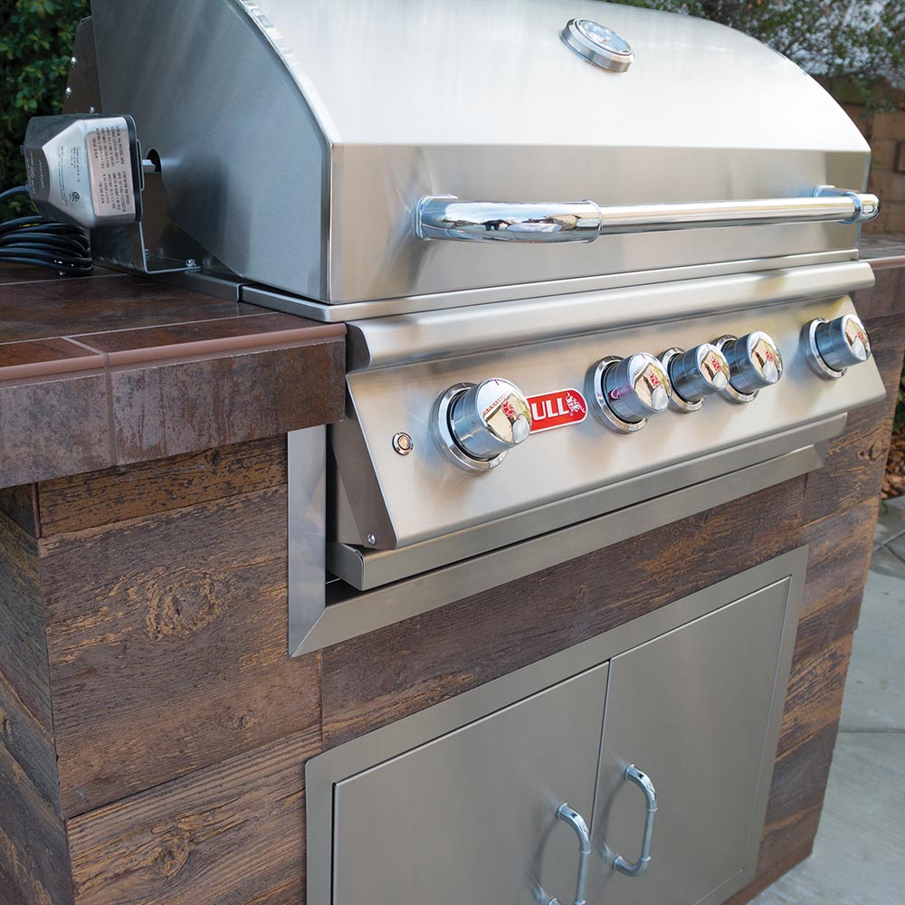 Built-in stainless steel grill with control knobs and side shelf on cabinet base