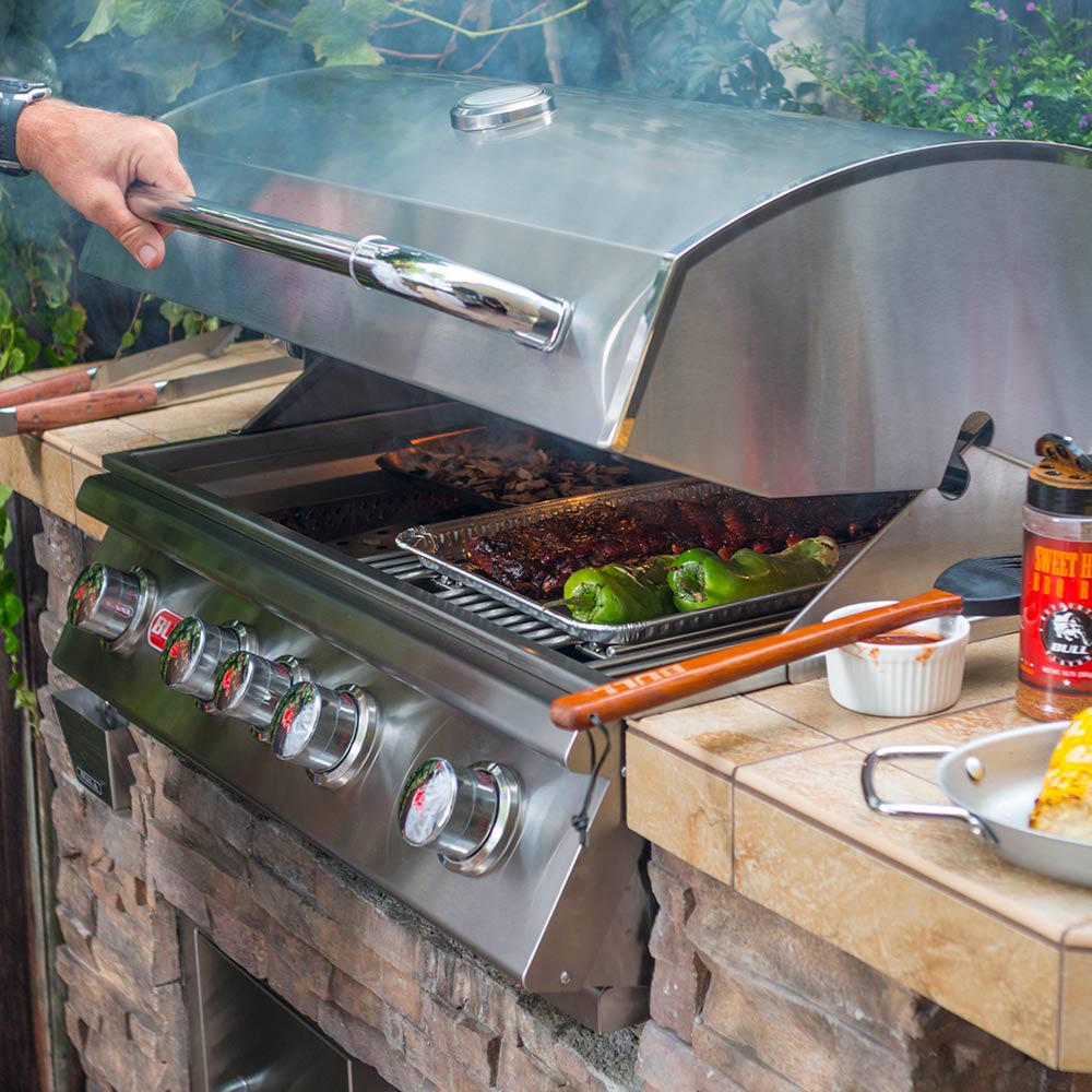 Stainless steel grill with open hood and cooking grate, food grilling over flames