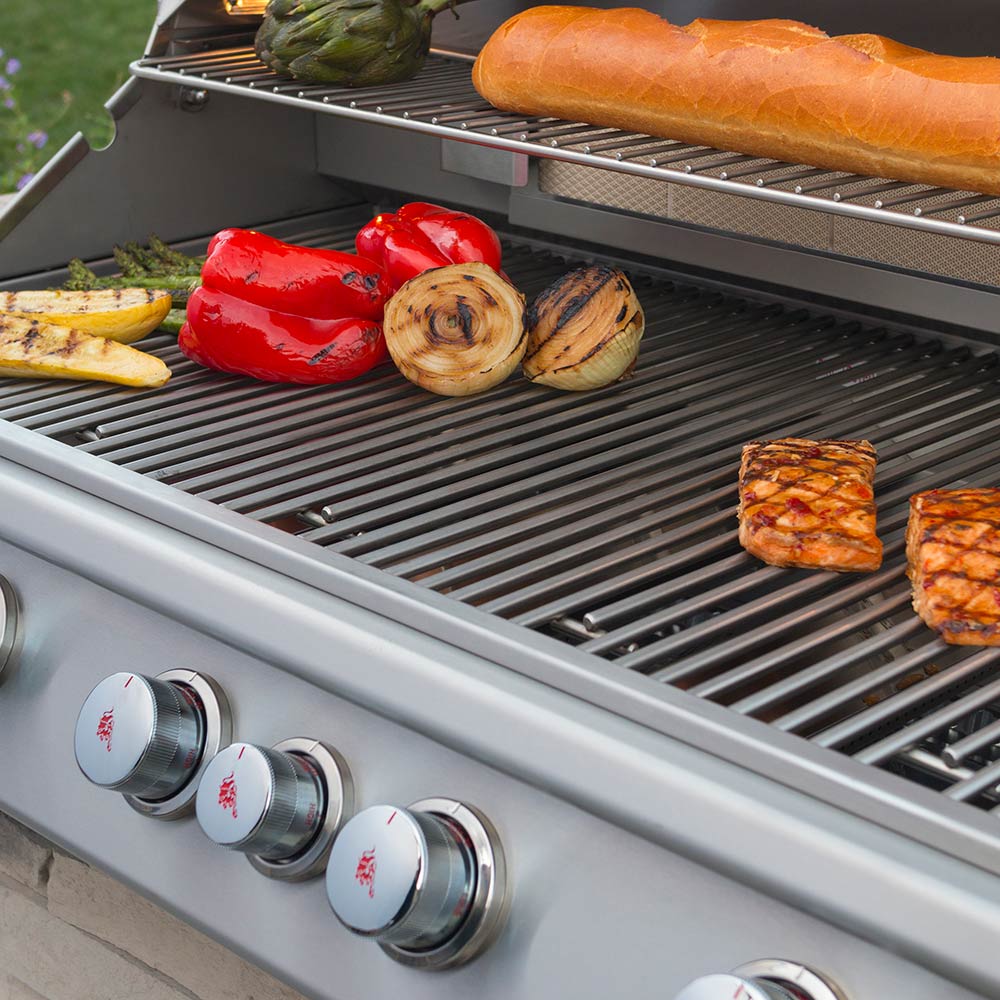 Built-in grill with sausages, onions, peppers, and burgers on stainless grates