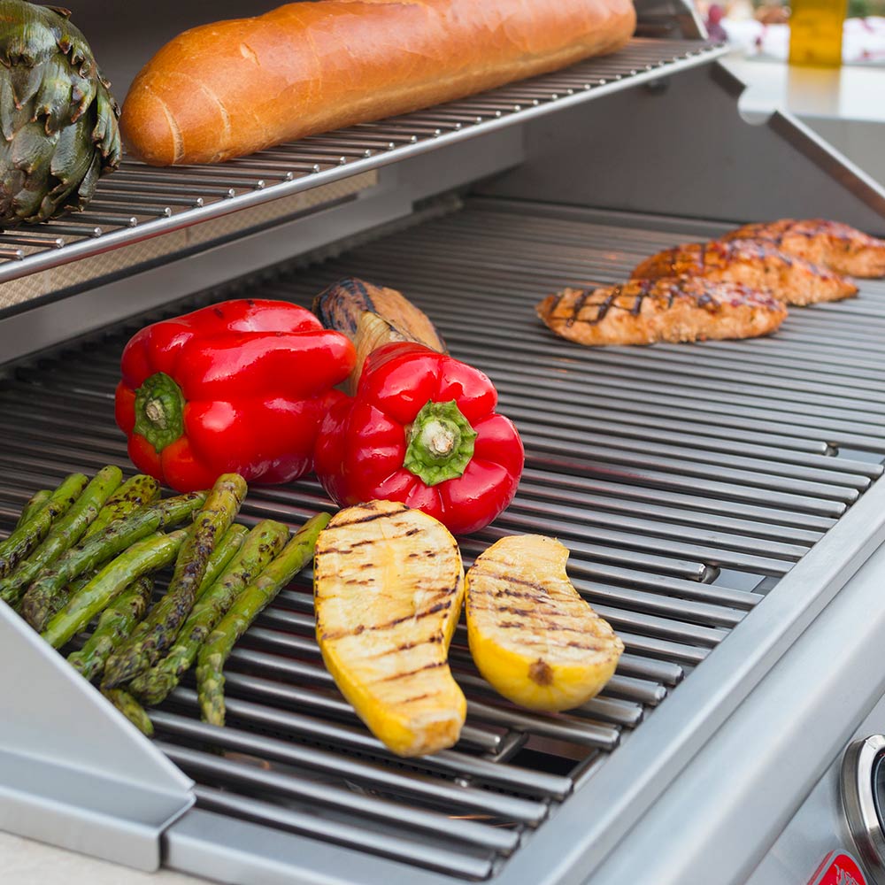 Open built-in grill with sausages, squash, and peppers on ridged grates
