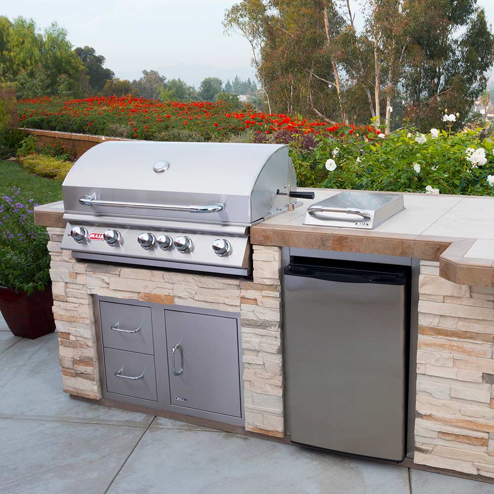 Outdoor stainless grill in stone cabinet with side burner and control knobs