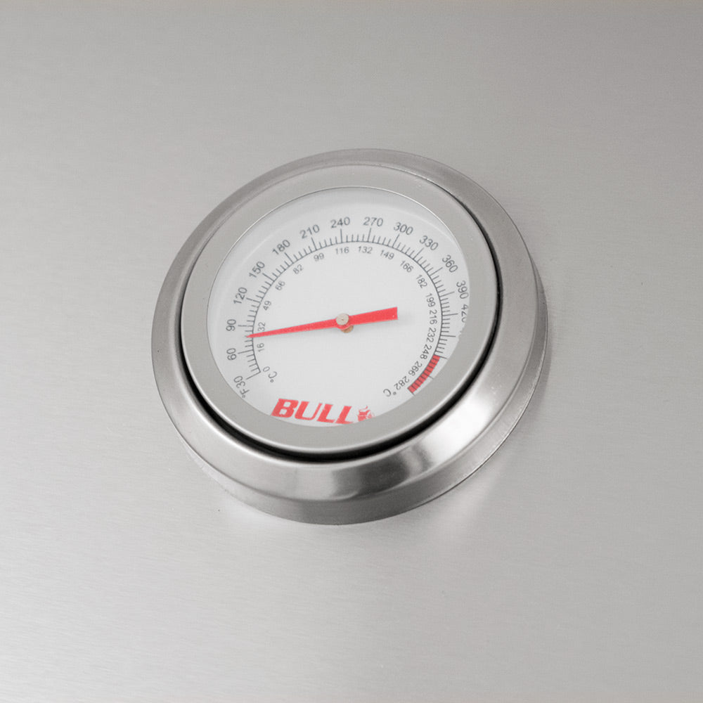 Built-in temperature gauge with red needle on stainless charcoal grill hood