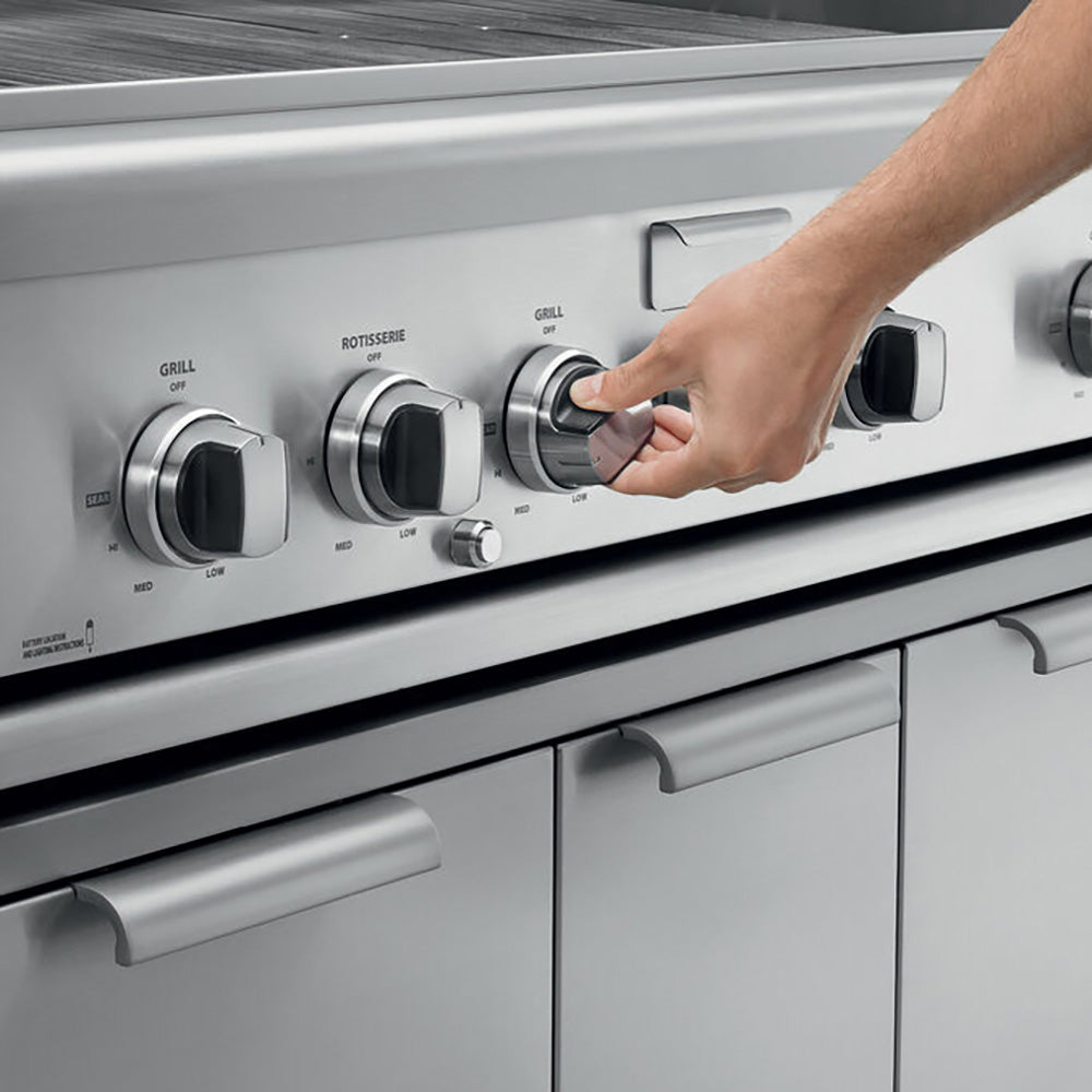 Built-in gas grill control panel with multiple knobs and a hand turning one