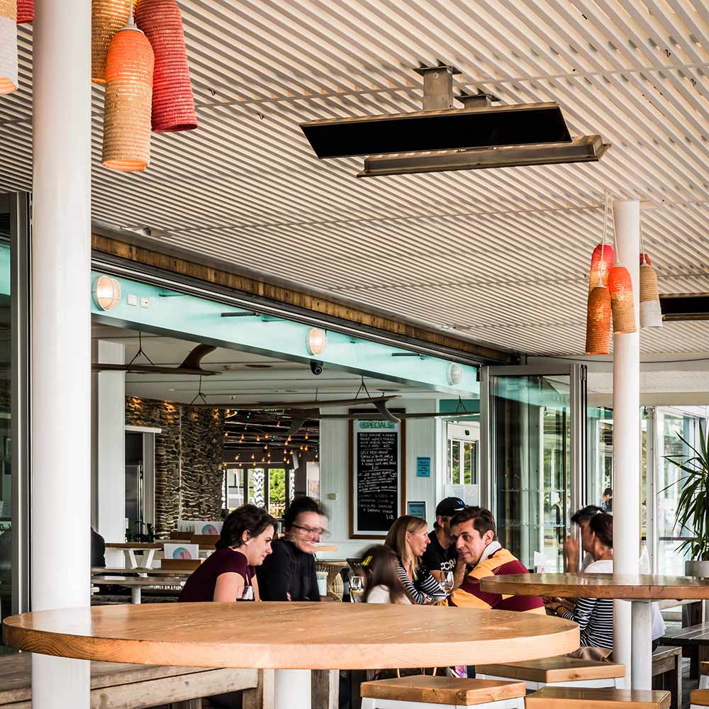 Ceiling-mounted electric heater with black housing under a patio roof.