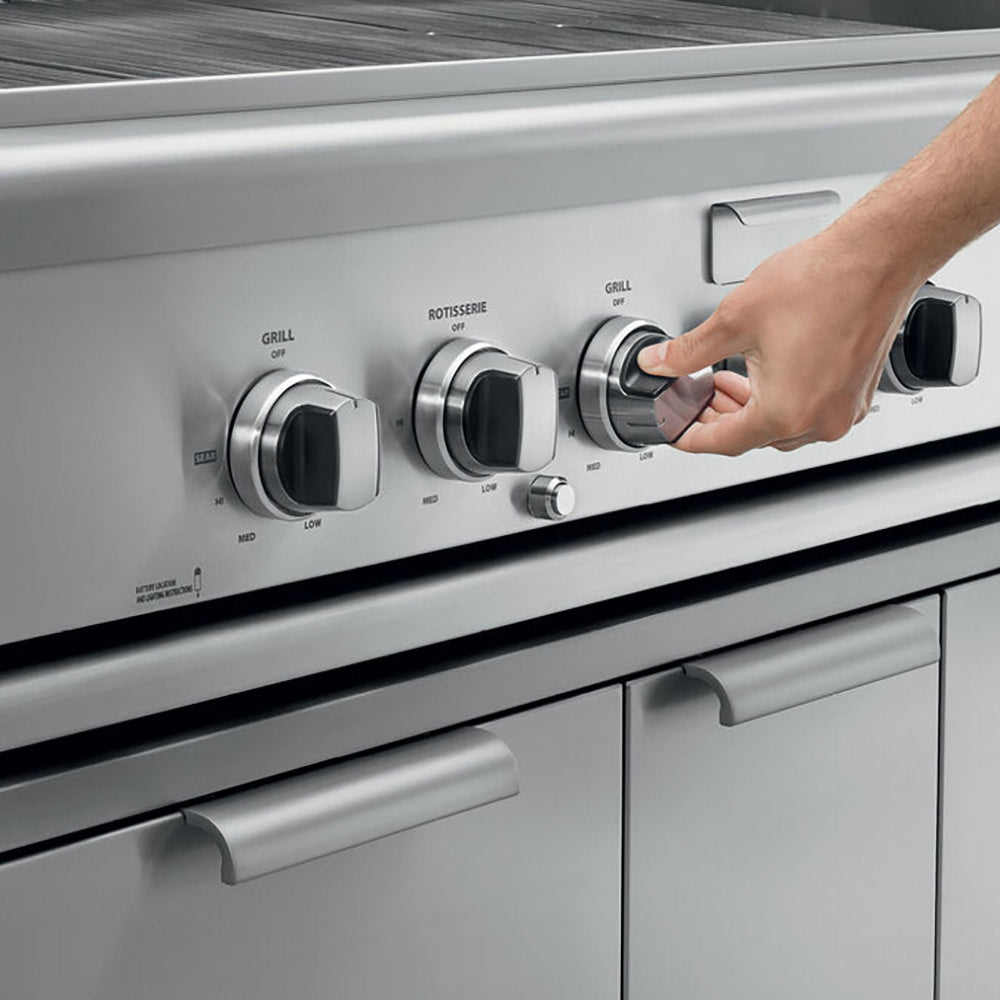 Built-in gas grill control panel with round knobs, hand adjusting a rotisserie/grill setting