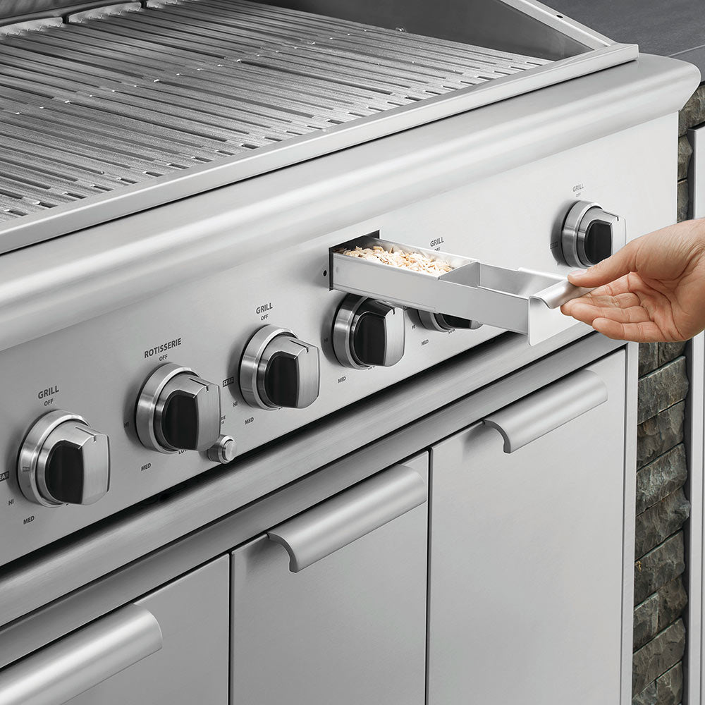Built-in gas grill with open hood, stainless control knobs, and side burner tray