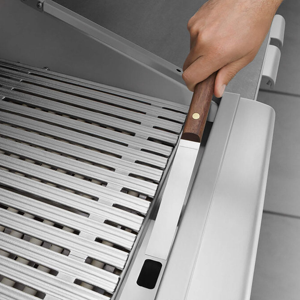 Hand lifting a side cover next to stainless steel grill grates