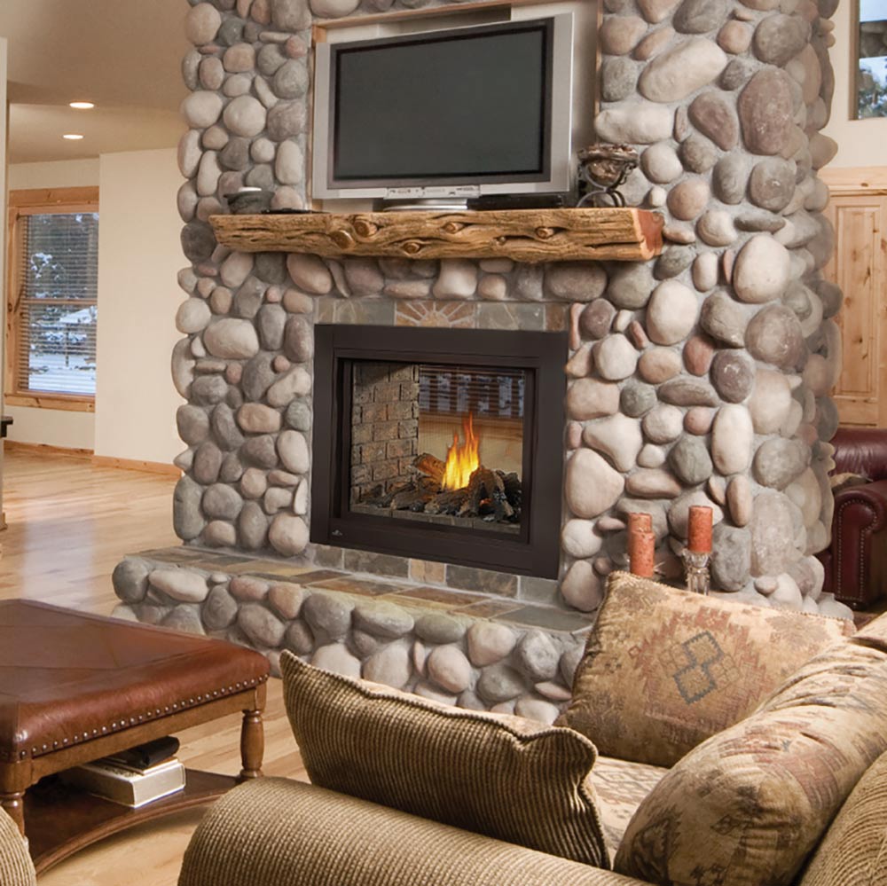 Black gas fireplace insert in stone wall surround with burning logs
