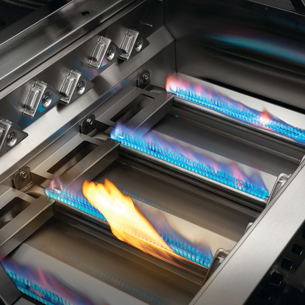 Built-in gas grill firebox with multiple burners lit inside stainless steel housing