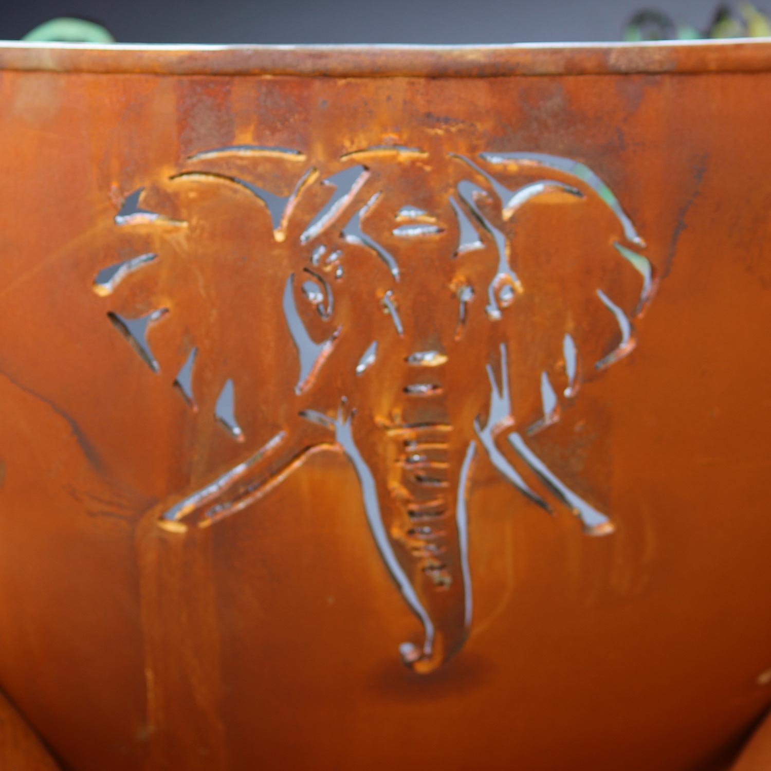 Orange steel fire pit bowl with raised lion cutout detail and patterned border.
