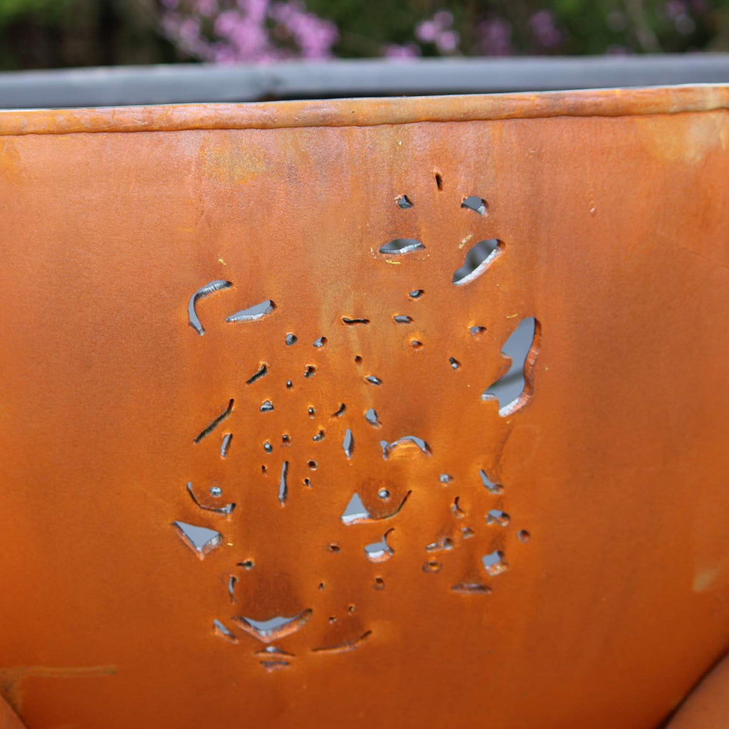 Orange steel fire pit bowl with animal cutout silhouette and small perforations.