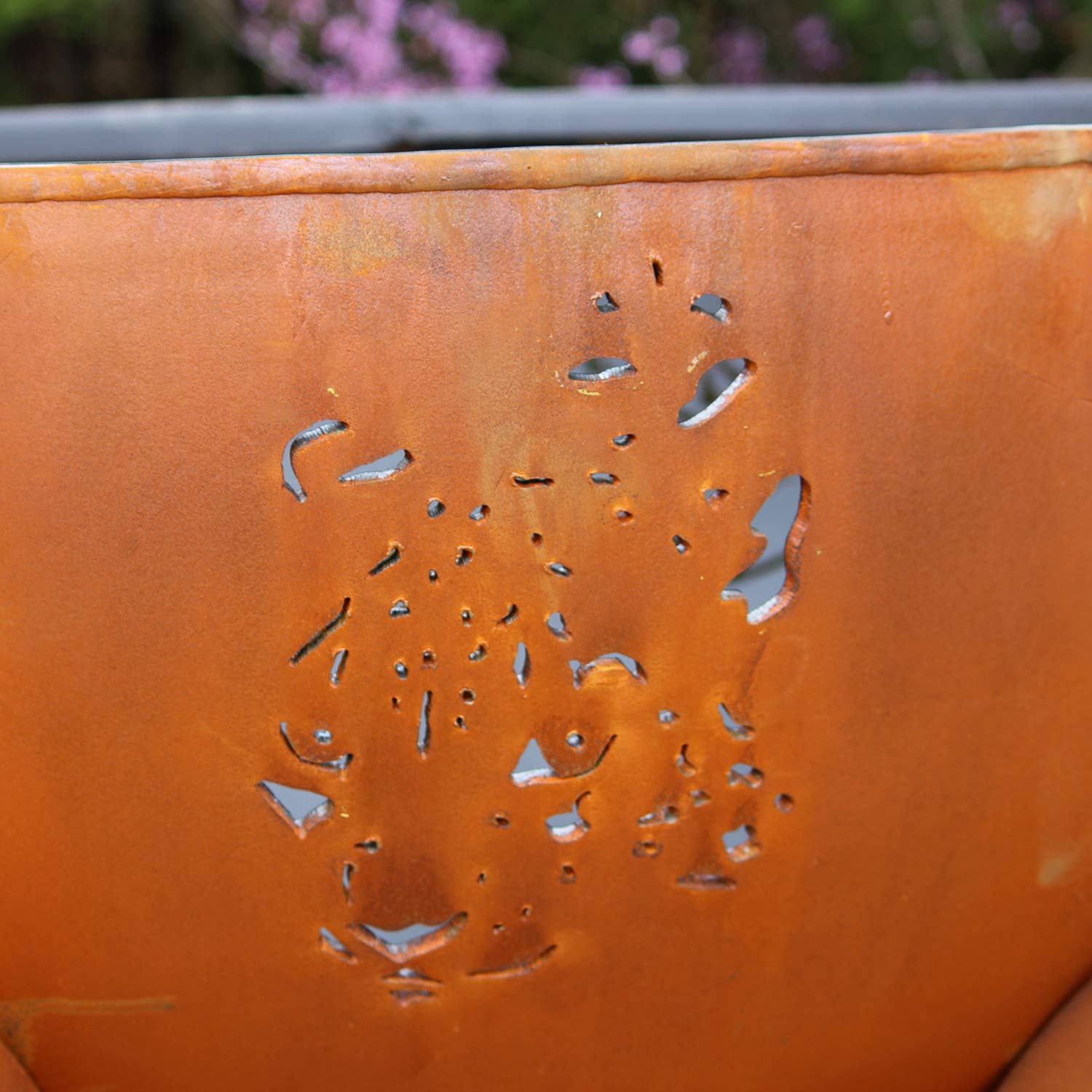 Orange steel fire pit bowl with animal cutout silhouette and small perforations.
