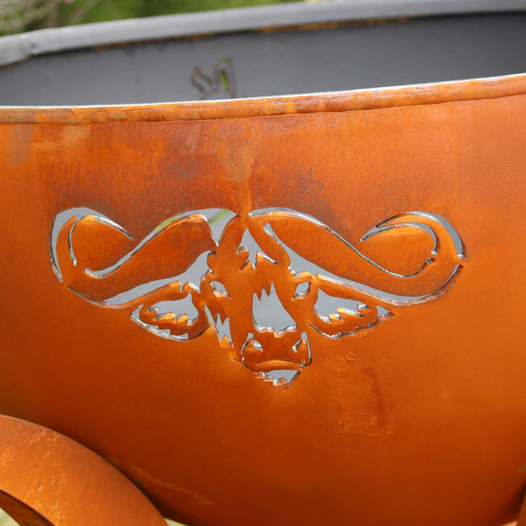 Orange steel fire pit bowl with elephant-style cutout and curled handle-like supports.