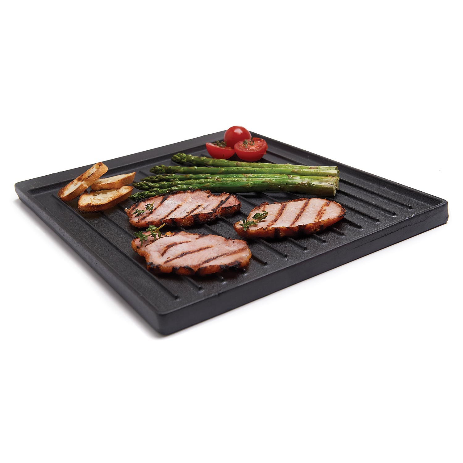 Cast iron griddle with grilled pork, asparagus, and tomato halves on raised ridges