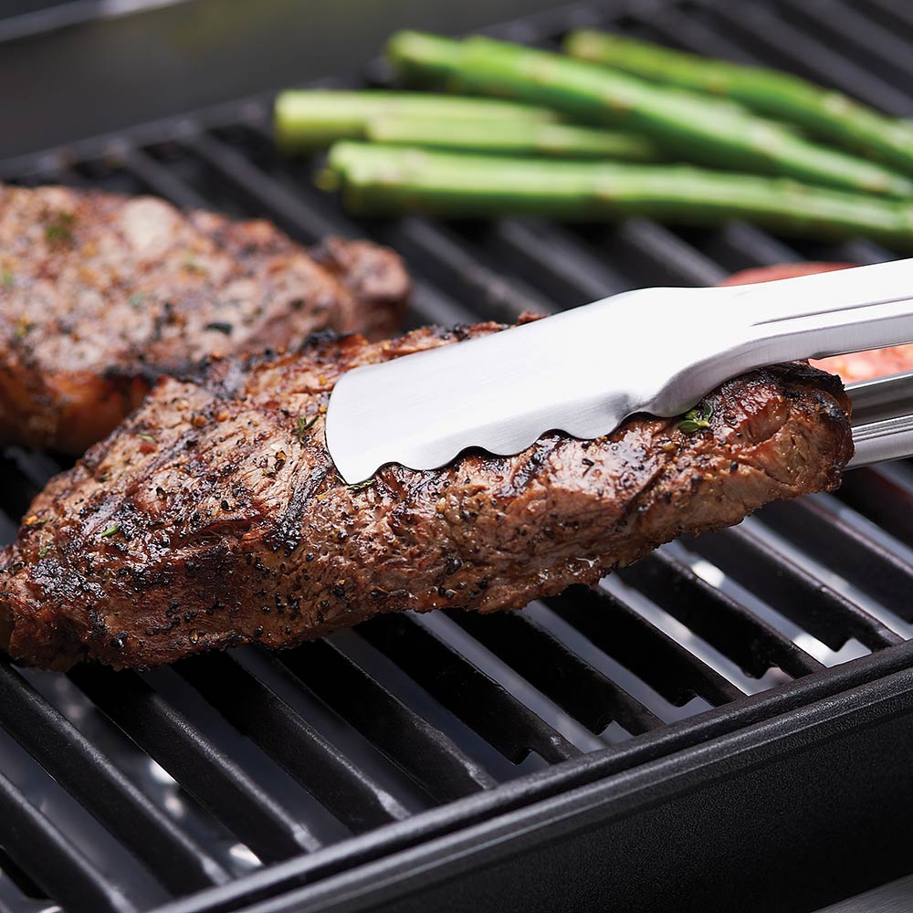 Cast iron cooking grid with seared steak on grill bars and a spatula