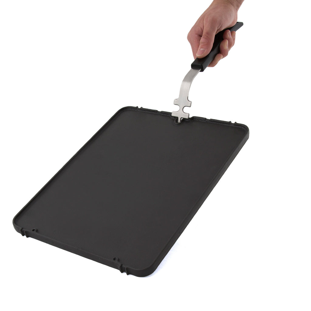 Cast iron griddle insert lifted by handle, smooth cooking surface