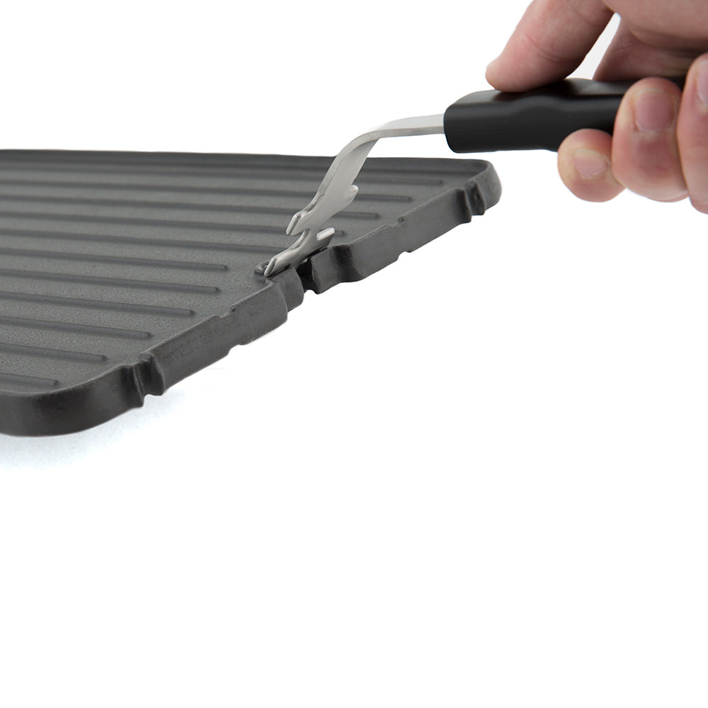Cast iron griddle lifted with metal handle tool attached