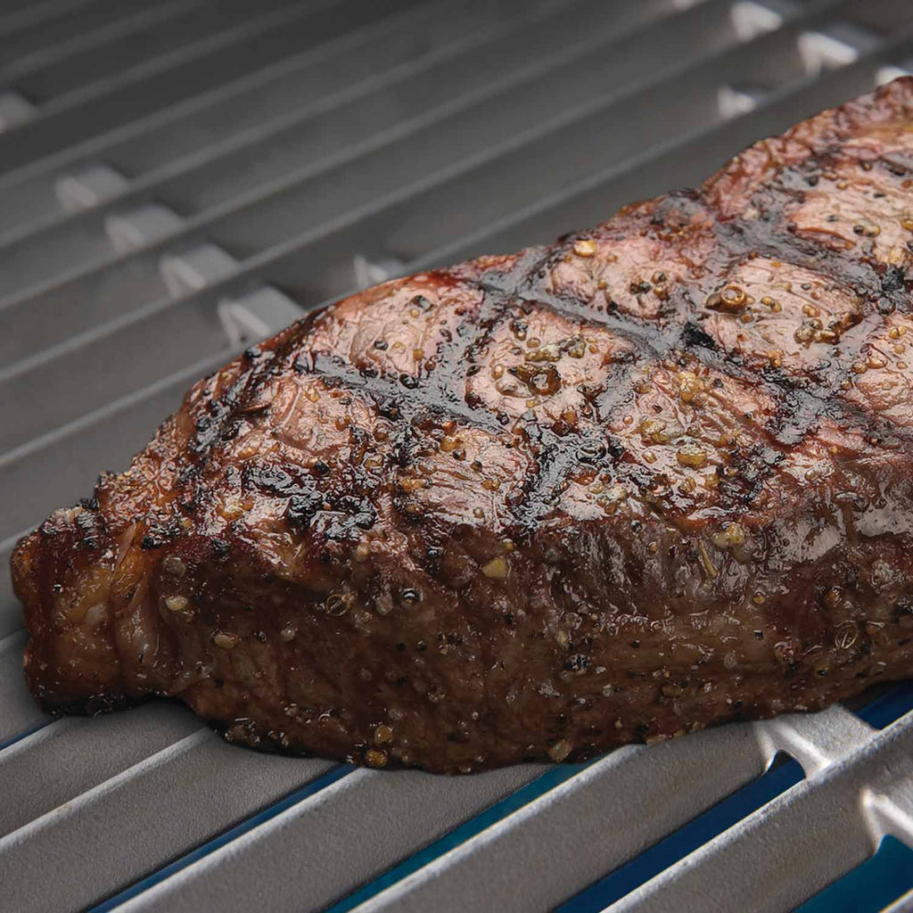 Steak resting on a stainless steel cooking grid