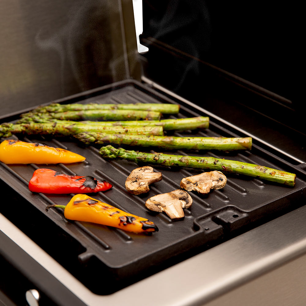 Cast iron griddle plate with asparagus, peppers, and mushrooms cooking