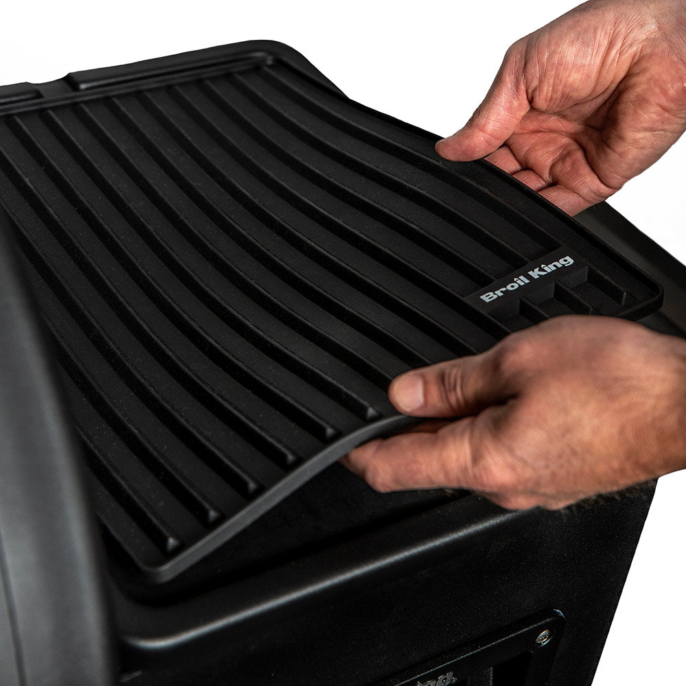 Black silicone side shelf mat being placed on grill, ridged pattern